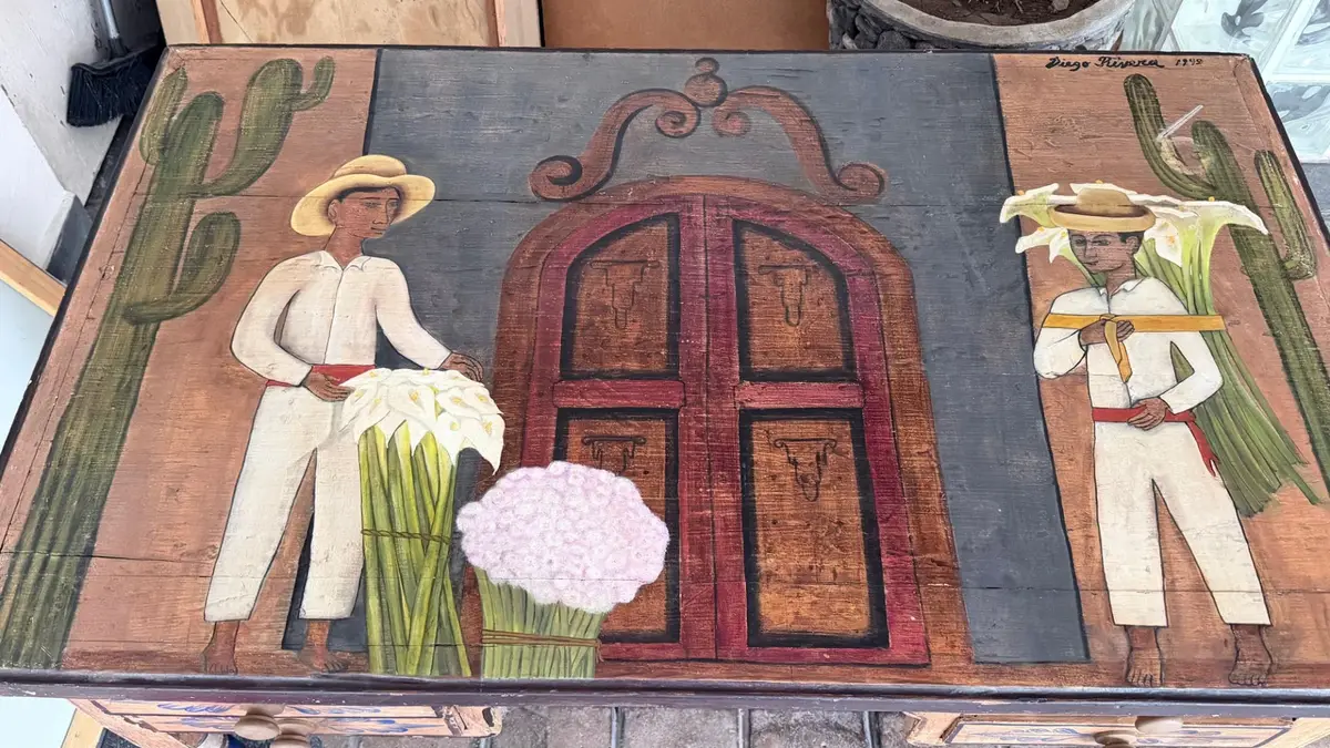 Cubierta pintada del escritorio: dos cargadores de alcatraces junto a una puerta colonial, con la inscripción Diego Rivera 1949 arriba a la derecha