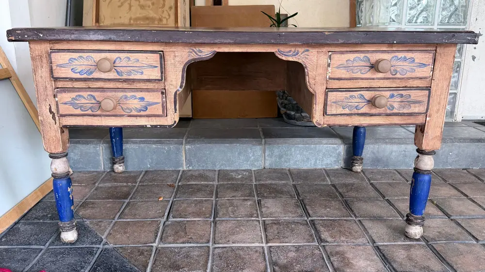Vista frontal del escritorio con cuatro cajones decorados con hojas azules y patas torneadas